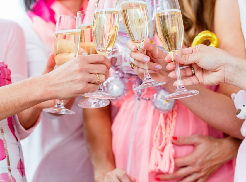 Close up of group of women, one pregnant, clinking champagne flutes together