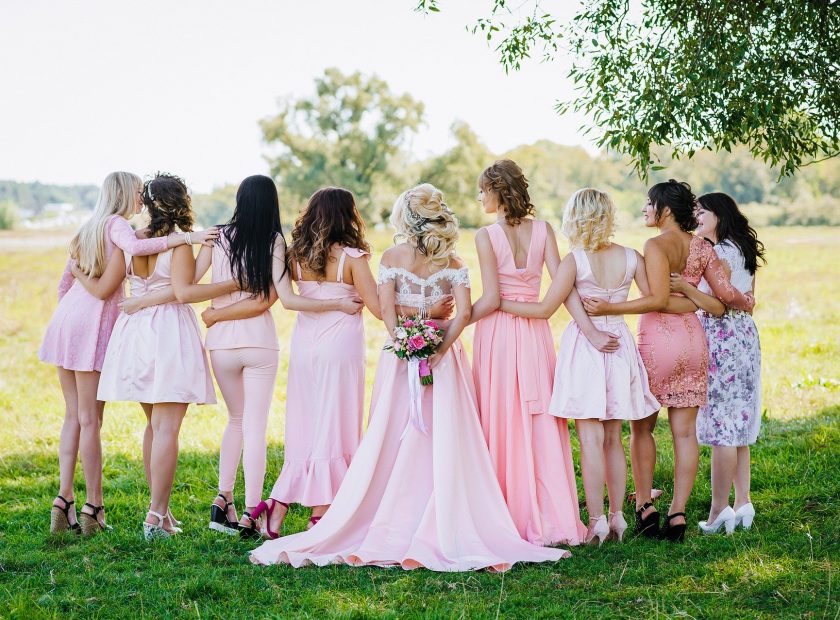 Photo of a bridal party from behind, in an outdoor location.